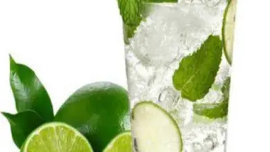 Sklenička s mojitom, ledem, mátou a limetkou na bílém pozadí.