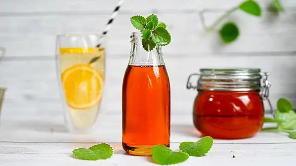 Sklenička sirupu s mátou vedle skla limonády