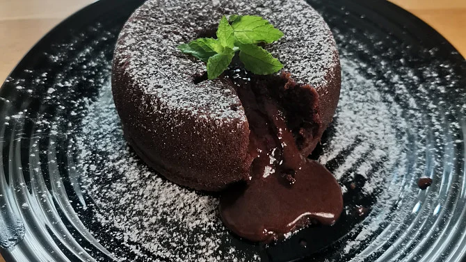 Čokoládový fondant s tekutým jádrem posypaný cukrářským práškem.