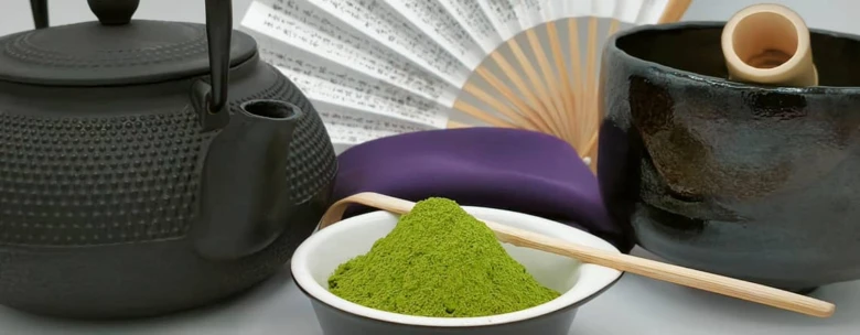Černý čajový hrnec s bambusovou šlehačkou a zeleným práškem matcha.