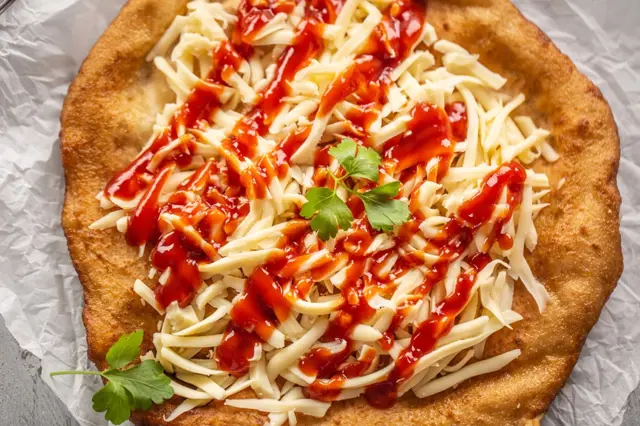 Uncooked langoš with cheese and sauce