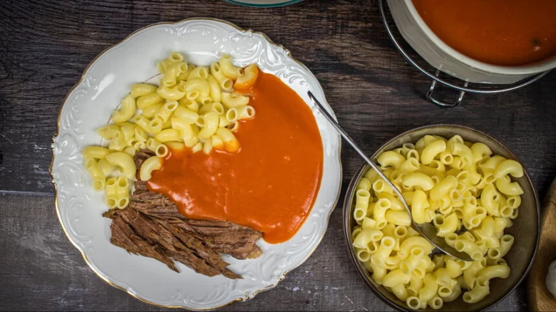 Pasta s rajskou omáčkou a masem na talíři.