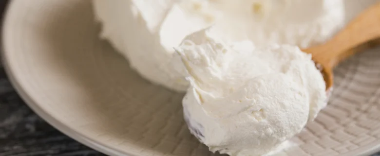 Bílá smetana na lžičce jako náhrada pro mascarpone v receptech.