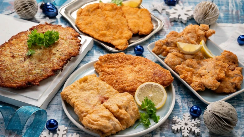 Různé obalené řízky s citronem a petrželkou na vánočním stolu.