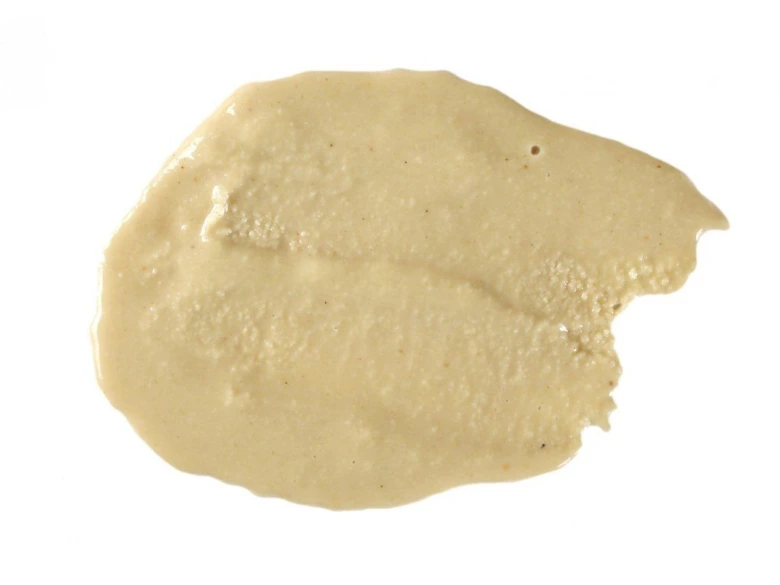 Pasta z tahini rozetřená na bílém pozadí.