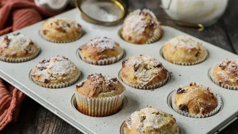 Tray s pečenými muffiny posypané cukrem pudrem.
