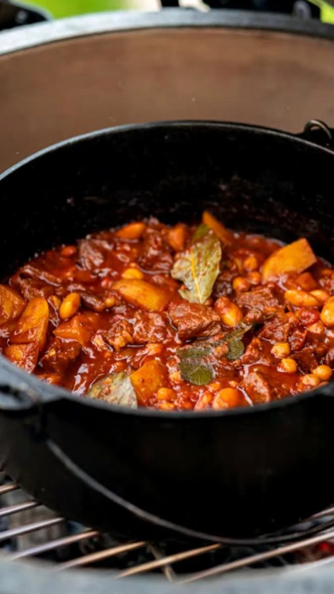 Hot fazolový guláš s masem a bramborem v hrnci na grilu.