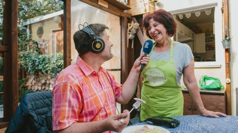 Muž interviewuje ženu v kuchyni s mikrofonem.