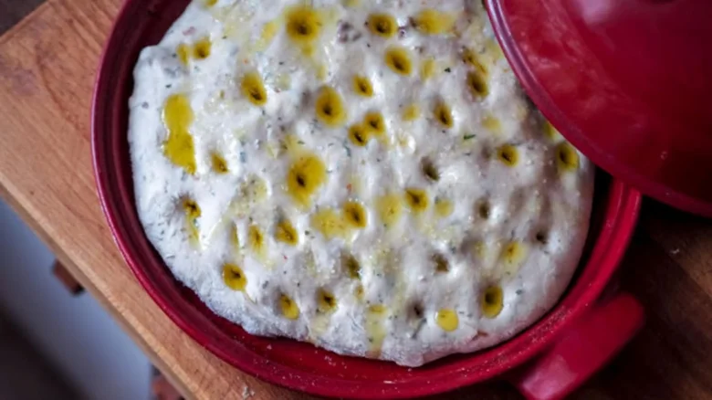 Nepečená italská focaccia s olivovým olejem v červené misce.