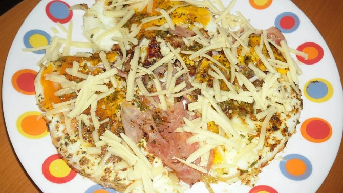 Omleta se slaninou a sýrem na talíři.