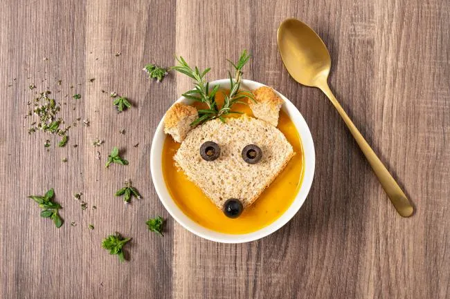 Kreativní miska zeleninové polévky s tvarem zvířete z chleba.