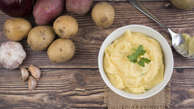 Míchané brambory s petrželkou a surovými ingrediencemi na dřevěném stole.