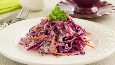 Salát coleslaw z červeného zelí na bílém talíři.