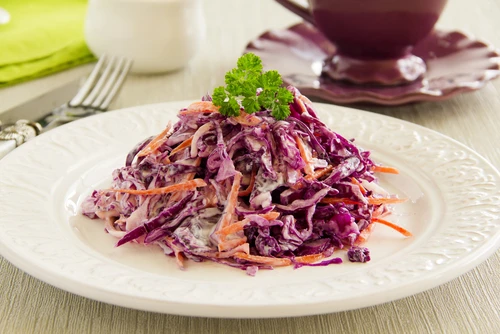 Salát coleslaw z červeného zelí na bílém talíři.