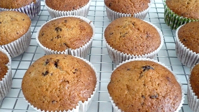 Zlatohnědé muffiny s čokoládou na mřížce pro chlazení.