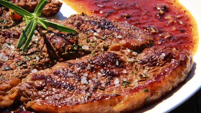 Připravený hovězí steak na pánvi s omáčkou a bylinkami
