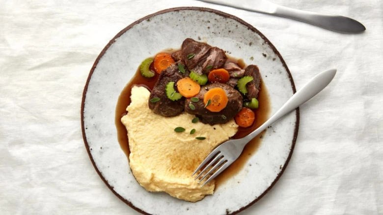 Slaná italská polenta s masem a zeleninou na talíři