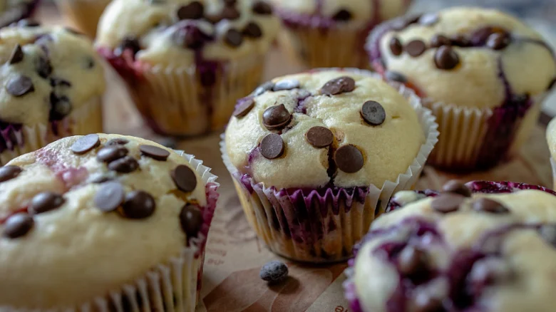 Muffiny s čokoládovými kousky a borůvkami v papírovém lístku.