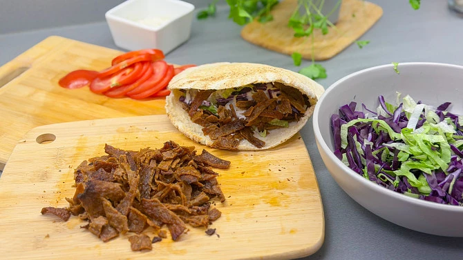 Domácí kebab s mletým masem na dřevěném prkénku.