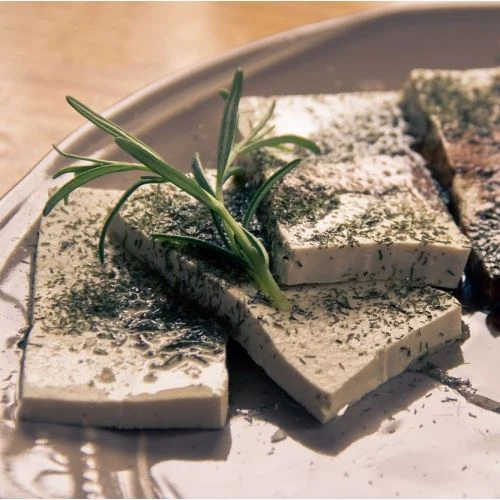 Kousky sezónovaného tofu s čerstvou rozmarýnem na talíři.