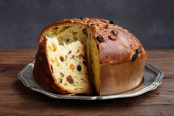 Tradiční italské panettone s odseknutým kusem na stříbrném podnosu.