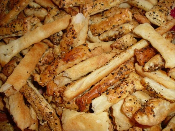 Zlatohnědé pruty listového těsta s osypanými semínky.