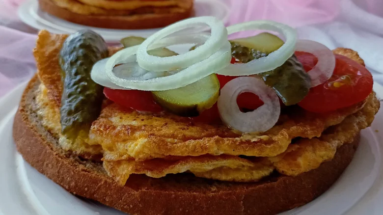 Tradiční česká smaženka s vejci, okurkami a cibulí na chlebu.