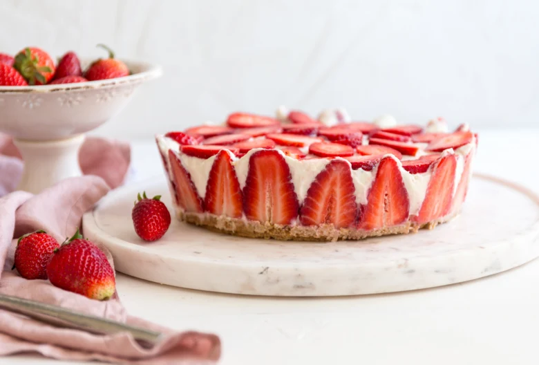 Strawberry cheesecake tart s čerstvými jahodami na mramorovém podstavci.