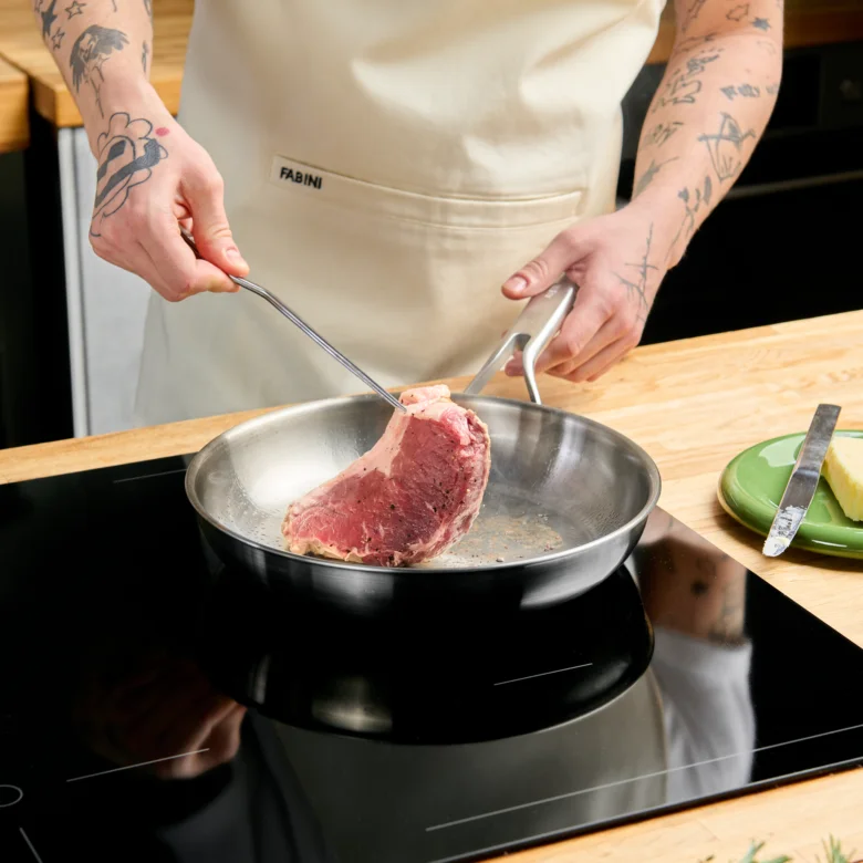 Kuchař smaží hovězí steak na pánvi.