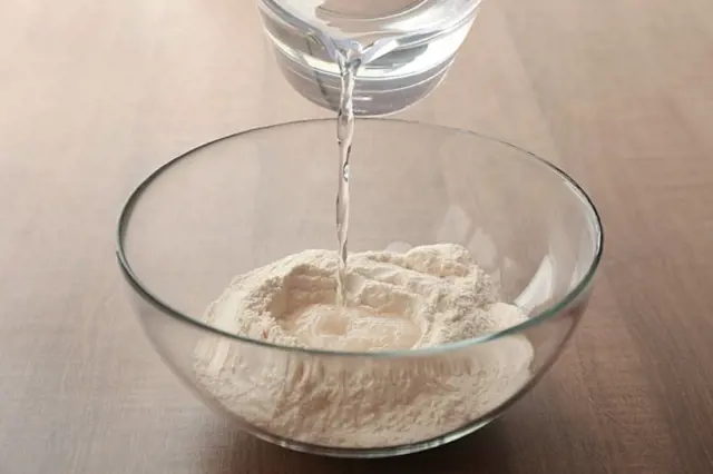 Voda se nalévá do mísy s moukou pro placky.