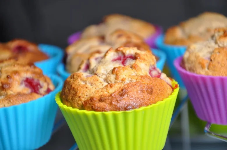 Zlatohnědé bezlepkové muffiny v barevných silikonových formách s viditelným ovocem.