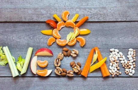 Různé ovoce a zelenina tvořící slovo veganské na dřevěném povrchu.