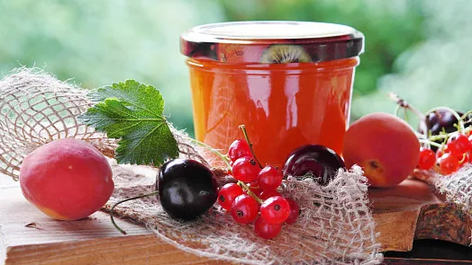 Sklenice domácí meruňkové marmelády s čerstvými ovocem.