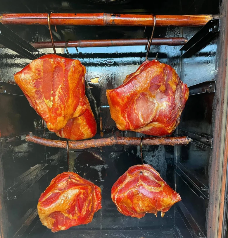 Čtyři kusy masa se uží v dřevěném kouřovém grilu.