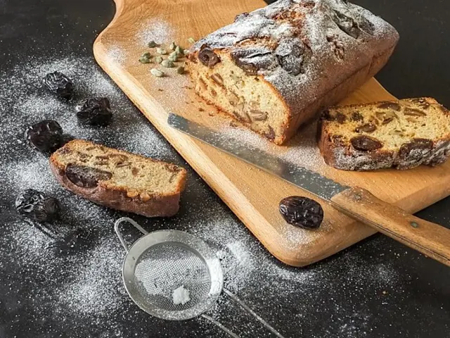 Ovocný chlebiček posypaný moučkovým cukrem na dřevěném prkénku.