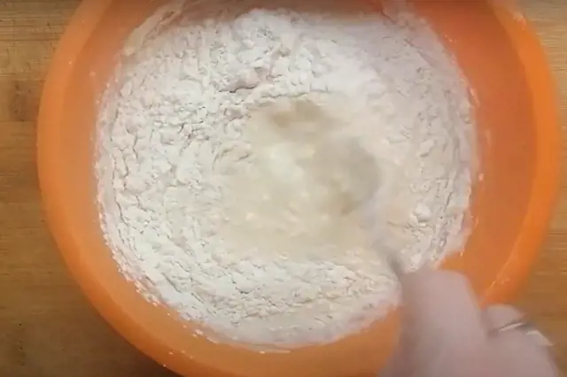 Míchání mouky s tekutinou v oranžové míse při přípravě řízků.