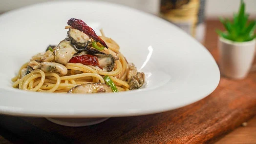 Pasta s mušlemi a paprikou na bílém talíři.