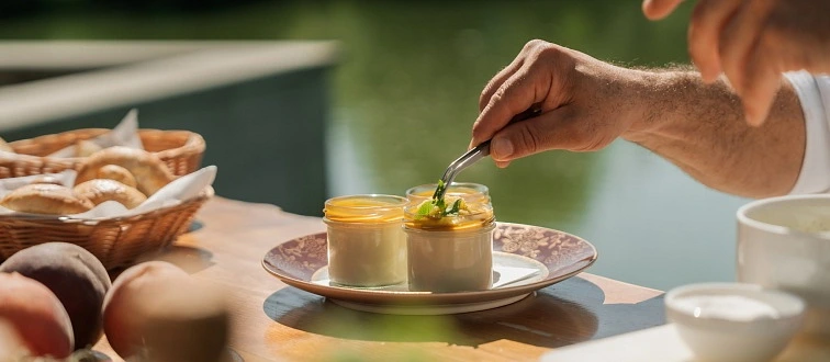Ruce servírují panna cottu ve skleničkách na talíři venku.