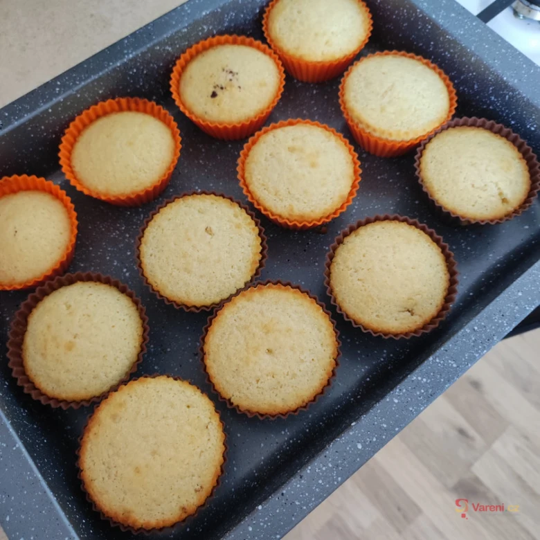 Zlatohnědé pečené muffiny v silikonových formách na plechu.