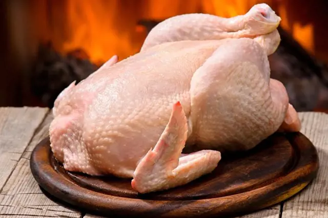 Raw whole chicken on wood board