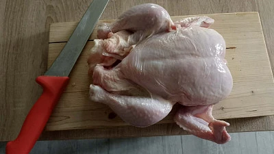 Syrové kuřecí prsa na dřevěném prknu s nožem.