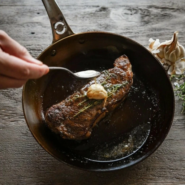 Rozpečený hovězí steak s česnekem na pánvi.