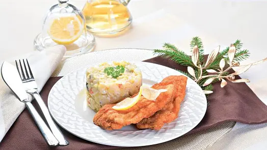 Malý předkrm s rybími plackami a rýžovým koláčkem ozdobeným citronovou kůrou na bílém talíři