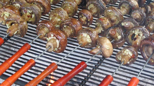 Grilované houby na špejlech s viditelnými znaky opálení.