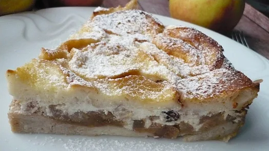 Kousek žemlovky z toustového chleba s jablky posypaný cukrem.