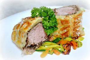 Kousek panenky Wellington s zeleninou na bílém talíři
