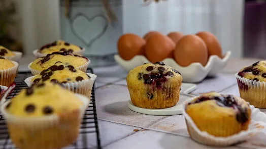 Svěží bezlepkové muffiny s borůvkami vedle vajec.