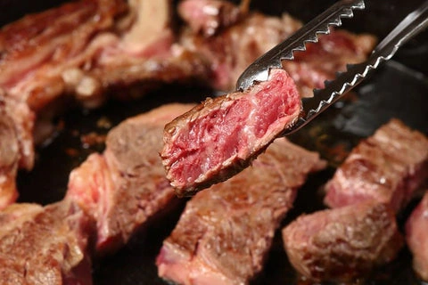 Připravené kusy hovězího steak na pánvi s viditelnou kůrou a šťavnatým vnitřkem.