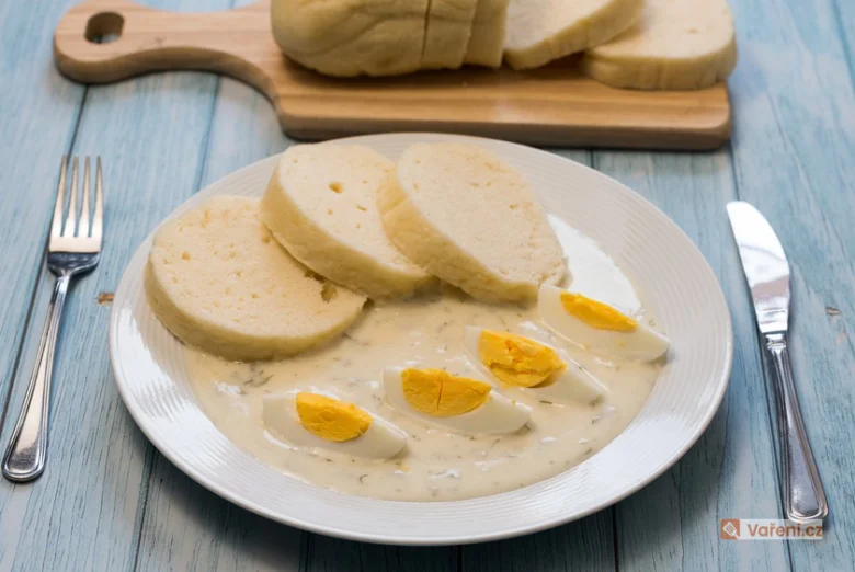 Připravené knedlíky bez housky s vejcem v omáčce na talíři.