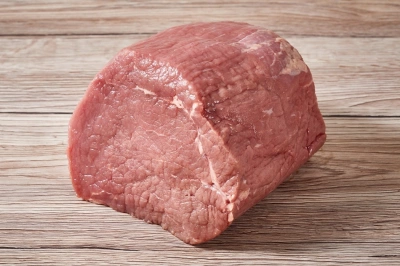 Kousek syrového hovězího masa na dřevěném povrchu.